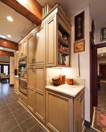 Custom floor-to-ceiling cabinetry under a wood-beam ceiling built by Armstrong Kitchens
