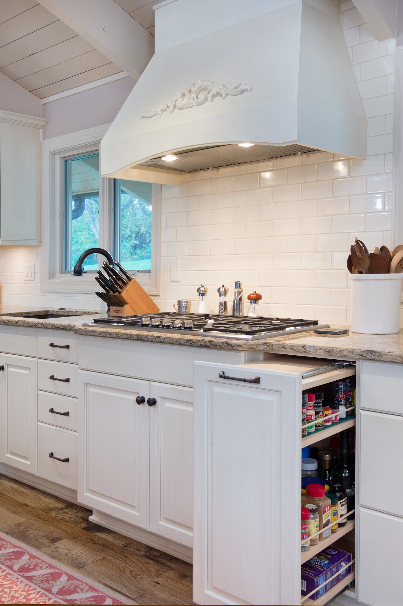 White kitchen with a custom range hood and a tiled backsplash by Armstrong Kitchens